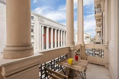 a balcony with a wooden table and chairs on a building at Ninni's House by DomuSicily in Palermo