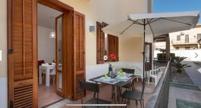 a dining room with a table and an umbrella at Blue Coral in San Vito lo Capo