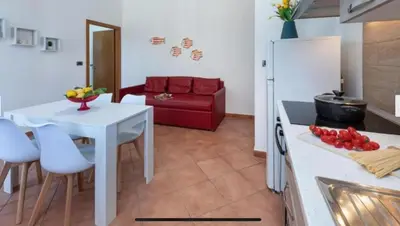 a kitchen with a white table and a red couch at Blue Coral in San Vito lo Capo