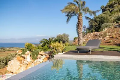 a chair sitting next to a swimming pool at Sea View Villa whit Pool in Scopello