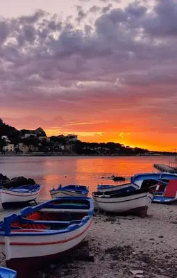 a group of boats sitting on the beach at sunset at Proserpina House in Palermo