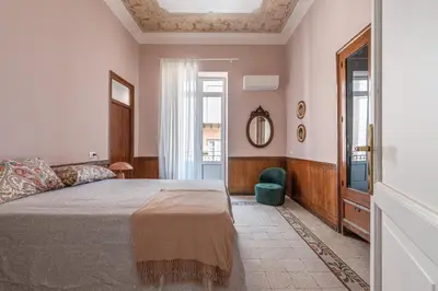 a bedroom with a bed and a window and a mirror at Stylish apartment near Piazza Magione by Wonderful Italy in Palermo