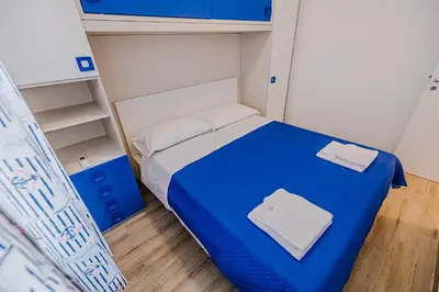 a small bedroom with a blue bed and shelves at Villa delle Palme in Campofelice di Roccella