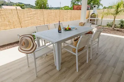 a white table and chairs with a bottle of wine at Villa delle Palme in Campofelice di Roccella