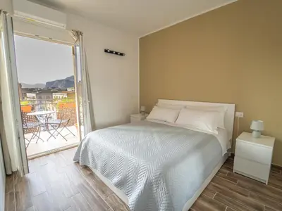 a bedroom with a bed and a balcony with a table at Central Station Home - Fanale Rentals in Palermo