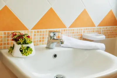 a bathroom sink with flowers and a faucet at Casa Longo 2 in Castellammare del Golfo