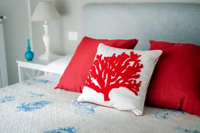 a bed with two pillows and a red pillow with a crab on it at Villa Marina Sant'Elia in Santa Flavia
