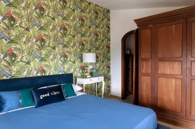 a bedroom with a blue bed and a wall with a bird pattern at Villa Marina Sant'Elia in Santa Flavia