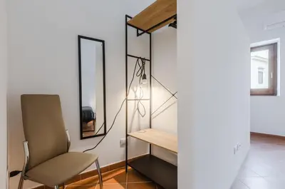 a room with a chair and a desk and mirror at GuestHost - Ballarò Cozy Apartment with Balconies in Palermo