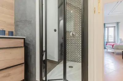 a glass shower in a room with a living room at GuestHost - Ballarò Cozy Apartment with Balconies in Palermo