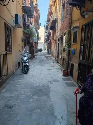 a woman walking down an alley with a scooter at Palermo Al Capo in Palermo