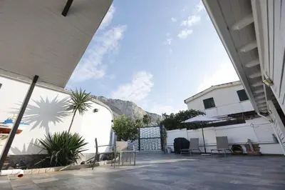 a house with two garages and chairs in a courtyard at Al Cottage Isola Delle Femmine in Isola delle Femmine