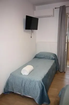a small bedroom with a bed and a flat screen tv at DUE CAPPUCCINI in Palermo
