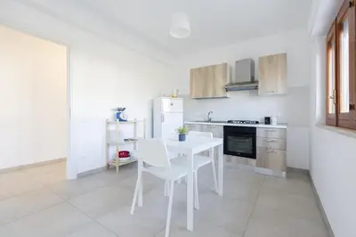 a white kitchen with a white table and chairs at Visitsicilia Rosetta Mare in Alcamo Marina