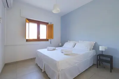 a white bedroom with a white bed and a window at Visitsicilia Rosetta Mare in Alcamo Marina
