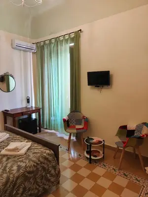 a hotel room with a bed and a tv and chairs at B&B Palazzo Corvino in Palermo