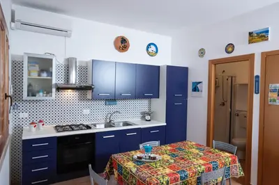 a kitchen with blue cabinets and a table and a sink at Casa Sally con Vista Mare a Macari in Macari