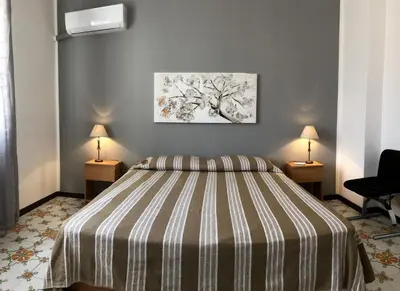 a bedroom with a bed with a striped bedspread and two lamps at Villa Gelvi in Castellammare del Golfo