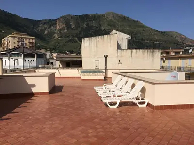 a group of white lounge chairs on a roof at Villa Gelvi in Castellammare del Golfo