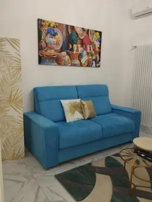 a blue couch in a living room with a painting at casa nike in Palermo