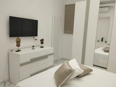 a white bedroom with a television on a white dresser at casa nike in Palermo