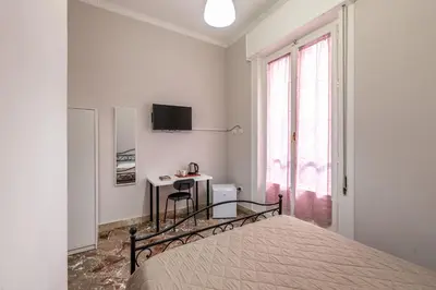 a white bedroom with a bed and a desk at LA VECCHIA PALERMO in Palermo