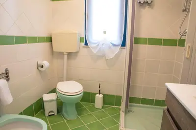 a small bathroom with a toilet and a shower at Beddamuri home in Carini