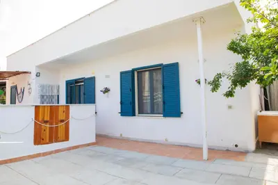 a white house with blue shutters and a courtyard at Beddamuri home in Carini