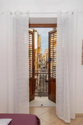 an open door to a balcony with white curtains at Quattrociocchi apartment in Bagheria