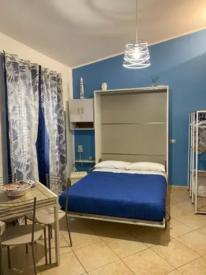 a blue bedroom with a bed and a table at La Dimora di David in Bagheria