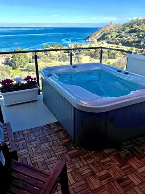 a hot tub on a balcony with a view of the ocean at TorreNormanna Prestige House near Cefalù in Mandra Capreria