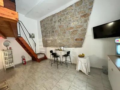 a room with a table and chairs and a stone wall at La casetta nel vicolo in Palermo