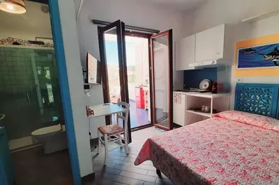 a bedroom with a bed and a table and a kitchen at Villa Mondello Terraces & Jacuzzi in Mondello
