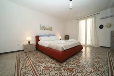 a bedroom with a large bed with a red couch at Colonna House Casa vacanze tra la Zisa e la Cattedrale in Palermo