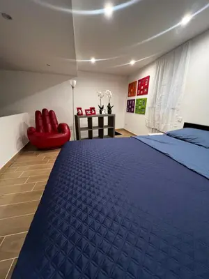 a bedroom with a blue bed and a red chair at Appartamento Beatrice in Palermo