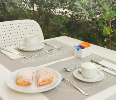 a table with two plates of donuts and cups on it at Butiko in Castelluzzo