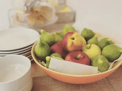 a bowl of apples and pears on a table at Butiko in Castelluzzo
