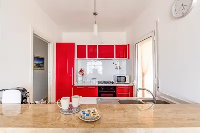 a kitchen with red cabinets and a counter top at Battigia Casa Vacanze-Alcamo Marina in Alcamo Marina