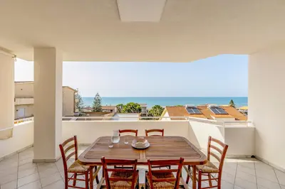 a dining room with a table and chairs and the ocean at Battigia Casa Vacanze-Alcamo Marina in Alcamo Marina