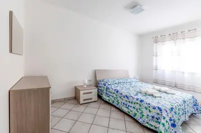 a white bedroom with a bed and a dresser and a bed sidx sidx sidx at Battigia Casa Vacanze-Alcamo Marina in Alcamo Marina