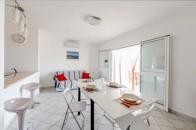 a white kitchen with a white table and chairs at Battigia Casa Vacanze-Alcamo Marina in Alcamo Marina