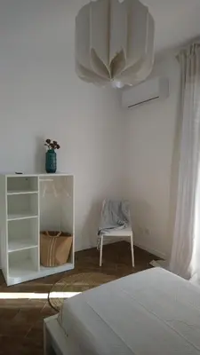 a white bedroom with a bed and a chair at Loft 407 in Cinisi