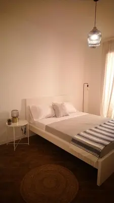 a white bedroom with a large bed and a table at Loft 407 in Cinisi
