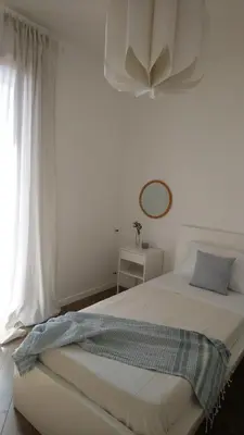a white bedroom with a bed and a window at Loft 407 in Cinisi