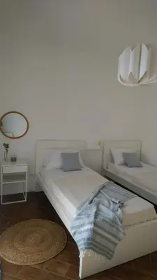 a white bedroom with two beds and a mirror at Loft 407 in Cinisi