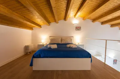 a bedroom with a bed with blue sheets and wooden ceilings at SHANTI HOLIDAY HOUSE in Palermo