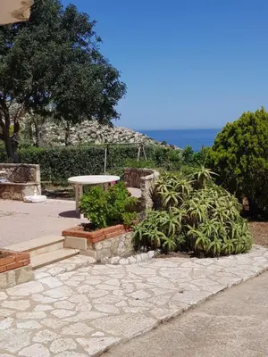 a stone patio with a table and some plants at Appartamenti Cala Rossa (Antonella) in Castellammare del Golfo