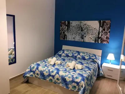 a bedroom with a bed with a blue wall at Case Saniela in Terrasini
