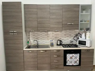 a kitchen with wooden cabinets and a sink and a microwave at Casa Corbezzolo in Balestrate