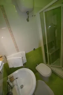 a green bathroom with a toilet and a sink at Il Muretto in Lascari